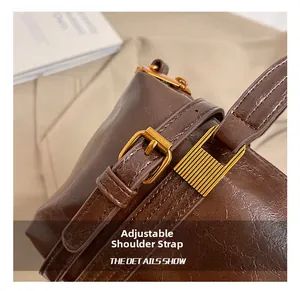 Detail of vintage brown leather bag showing adjustable shoulder strap with gold buckle