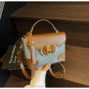 Detail of vintage small box bag featuring brown leather and blue denim patchwork with gold lock