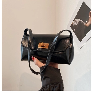 Détail d'un sac bandoulière vintage en cuir noir brillant avec un fermoir doré rectangulaire