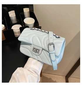 Close-up of light blue quilted leather bag with V-shaped stitching and chain strap