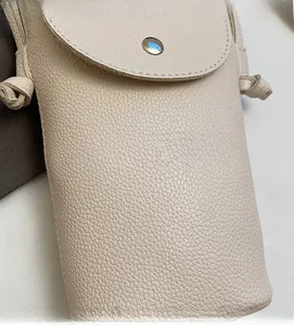 Detailed close-up of beige pebble grain leather texture with a metal snap button closure