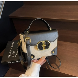 Close-up of contrast stitching and gold metal clasp on a vintage box bag displayed on stairs