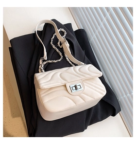 Close-up of cream quilted crossbody bag with wave pattern and silver twist lock detail