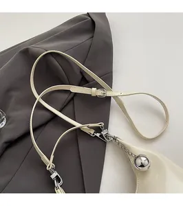 Détail du sac à main crème avec bandoulière réglable et pendentif boule argentée