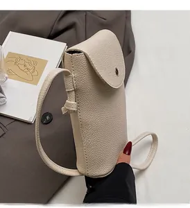 Detail of off-white lychee grain leather crossbody phone bag with flap and metal button