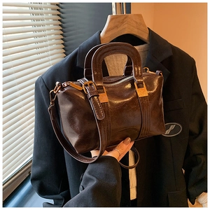 Detailed close-up of retro brown oily leather boston bag with gold hardware and hand strap