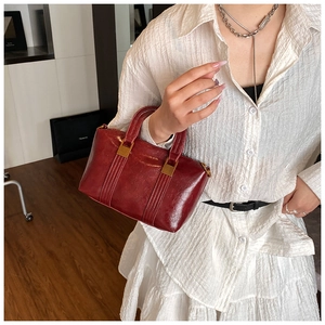 Close-up of vintage burgundy handbag with fine stitching and golden hardware