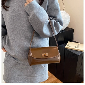 Gros plan du sac baguette marron vintage avec fermoir doré porté à l'épaule