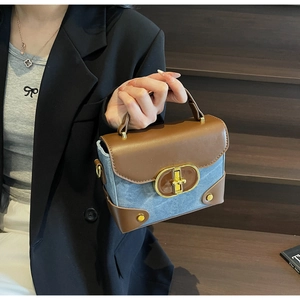 Detail of stylish color-block crossbody bag with denim and leather patchwork and gold lock