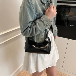 Détail du sac hobo noir avec ferrures argentées et breloque sphérique sur un mannequin