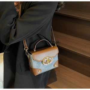 Blue denim crossbody box bag with brown leather trim and golden buckle on model