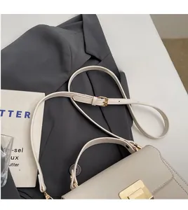 Detail of adjustable smooth shoulder strap and golden metal buckle on beige leather bag