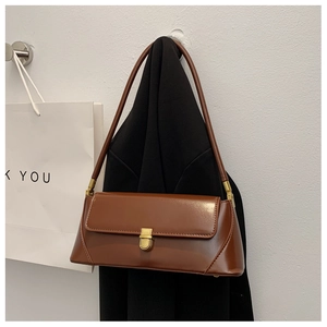 Detail of a brown leather baguette bag featuring a gold square clasp and shoulder strap