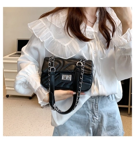 Detail of black quilted leather crossbody bag with silver twist lock and chain strap