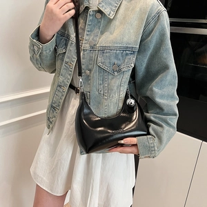 Détail du sac hobo noir brillant avec logo CLASSIC embossé et pendentif sphérique argent
