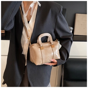 Close-up of beige faux leather boston bag with stitching details and golden hardware