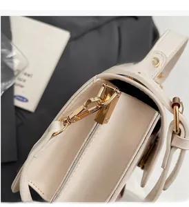 Close-up of premium white leather bag showing gold zipper and metallic hardware hooks