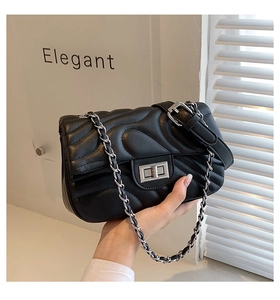 Close-up of black quilted bag featuring heart patterns and silver turn-lock clasp