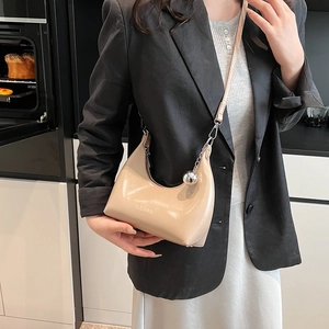 Détail du sac demi-lune beige avec breloque sphère argentée et logo CLEARCK sur cuir