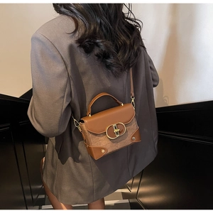 Brown vintage leather shoulder bag detail with gold ring buckle worn by a model