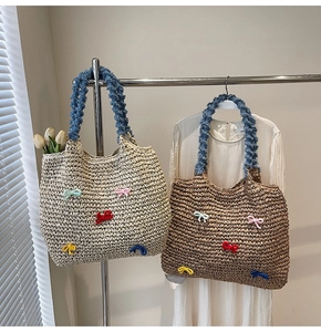 Detail of woven straw tote bag with colorful knitted bows and soft blue plush handles