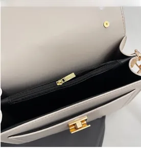 Detail of beige shoulder bag interior featuring black lining and gold zipper pocket