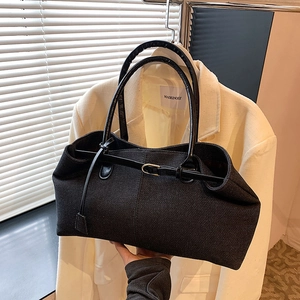 Grand sac cabas en denim noir avec anses en cuir et boucle dorée dans un studio de mode