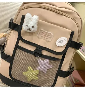 Front detail of khaki backpack featuring black mesh pockets and a plush rabbit pendant