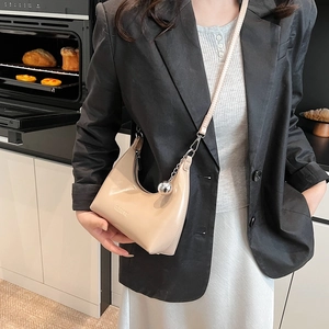 Détail du sac demi-lune beige avec pendentif boule argentée et logo CLEARX épuré