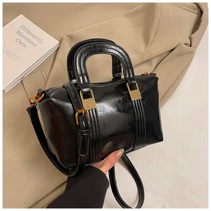 Detailed view of black oil wax leather handbag with retro gold hardware and stitching