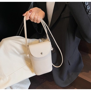 Close-up of a beige lychee pattern leather crossbody bag with silver buckle detail