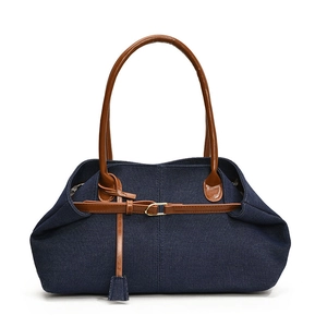 Sac fourre-tout en denim avec anses en cuir marron et boucle dorée sur fond blanc