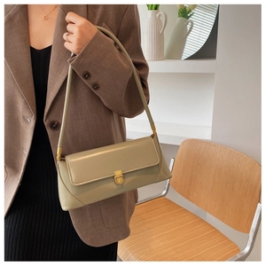 Detail of sage green baguette bag with gold metallic buckle and matte leather texture