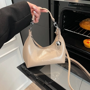 Détail du sac croissant beige avec breloque boule argentée et logo CLEAROK embossé