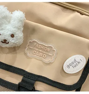 Detail of backpack with FASHION label, Good Luck patch, and white plush bunny charm