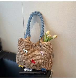 Detail of hand-woven straw tote bag with blue chenille handles and colorful bows decoration