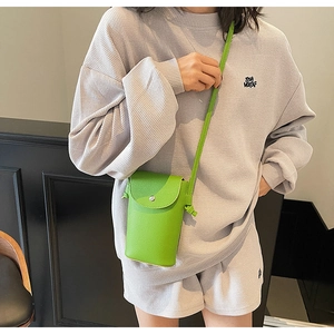 Detail of bright lime green pebbled leather crossbody bag with silver buckle and flap