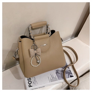 Detail of khaki pebbled leather bag featuring pearl charms and silver chain handles