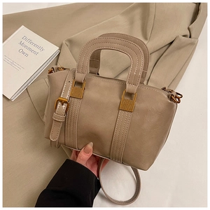 Top view of beige vintage leather handbag with gold hardware and dual handles on a blazer