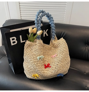 Detail of woven straw tote bag featuring colorful knit bows and soft blue plush handles