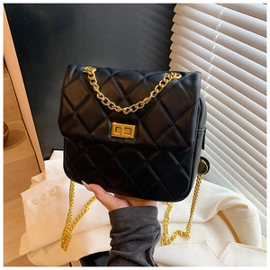 Close-up of black quilted leather texture and gold metal twist lock on the handbag