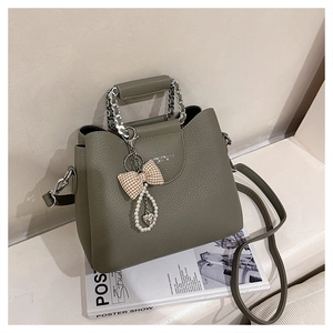 Close-up of olive green pebbled leather bag with chain handle and bow heart charm