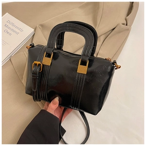 Macro detail of black glossy handbag with vintage golden hardware and stitching