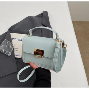 Detailed close-up of light blue mini square bag with golden lock and sleek leather texture