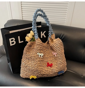 Detail of woven straw bag featuring colorful mini bows and light blue plush handle