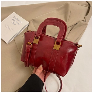 Detailed shot of dark red vintage boston bag with contrast stitching and antique gold hardware