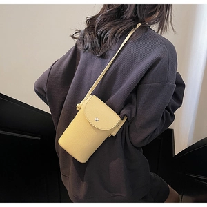 Close-up of yellow lychee textured leather crossbody bag with silver buckle on model
