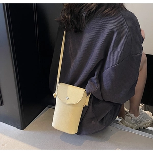 Detail view of yellow lychee pattern leather crossbody bag with magnetic metal clasp closure