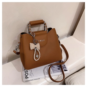 Close-up of brown litchi pattern leather bag with chain handle and decorative charm