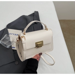 Detail of white PU leather crossbody bag featuring gold metal clasp and top handle